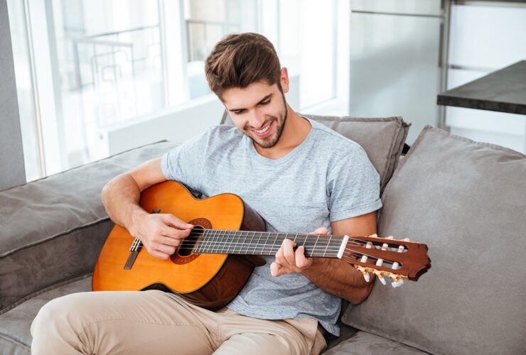 Man playing acoustic guitar at home during private in-home guitar lesson in Kelowna.