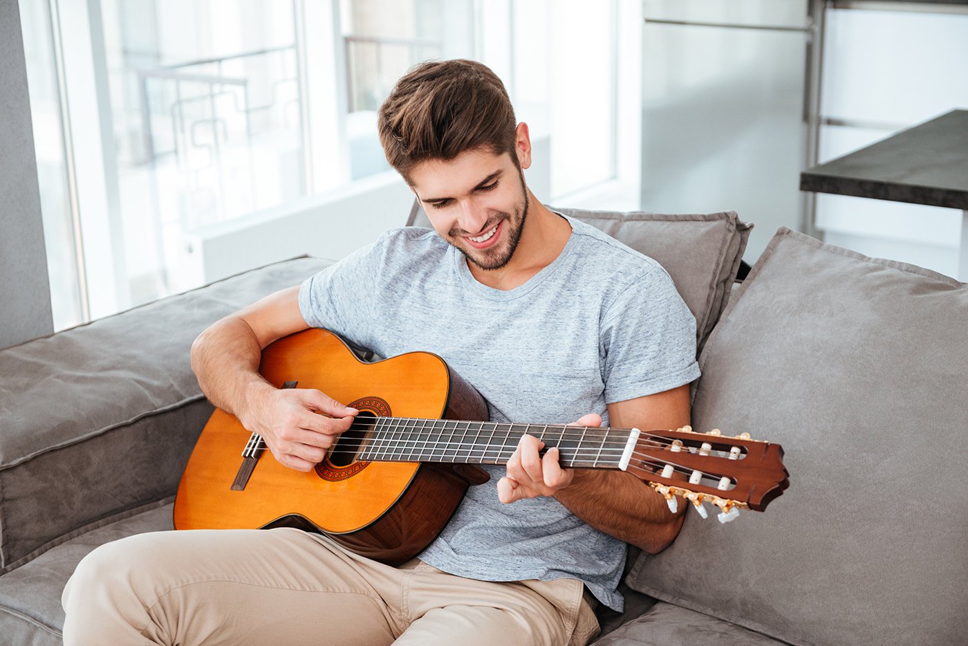 Man playing acoustic guitar at home during private in-home guitar lesson in Kelowna.