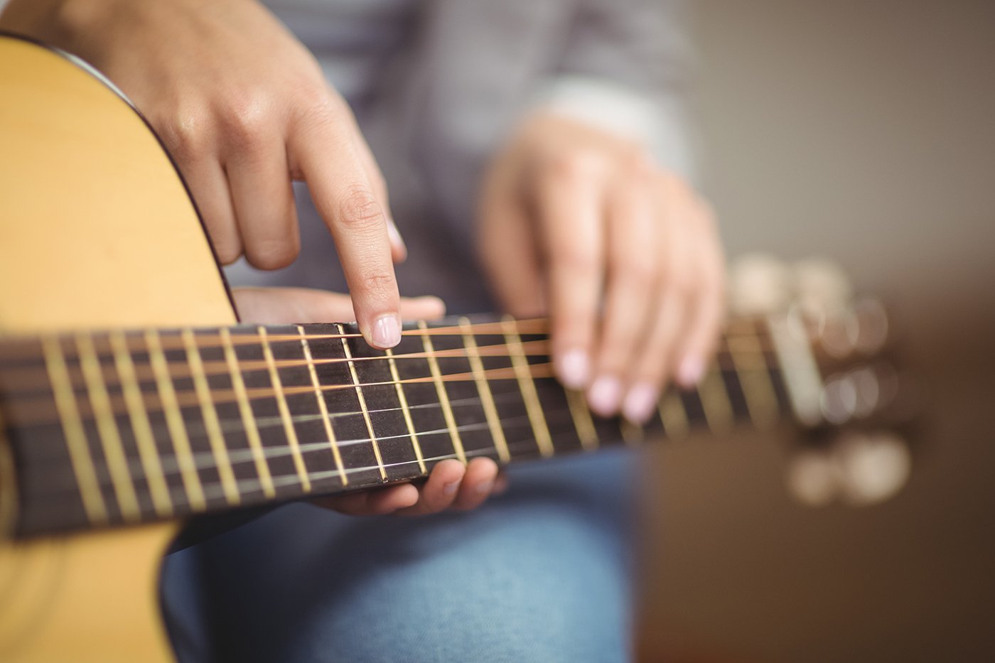 Kelowna guitar teacher giving private lesson, pointing at student’s acoustic guitar during practice.