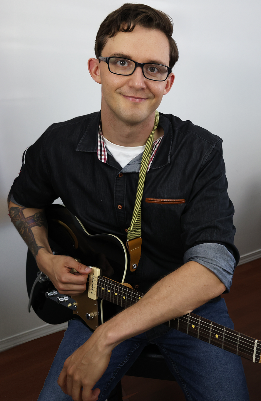 Local Kelowna guitar teacher from Upnotes Music sitting with a guitar, ready to teach students of all ages and skill levels.